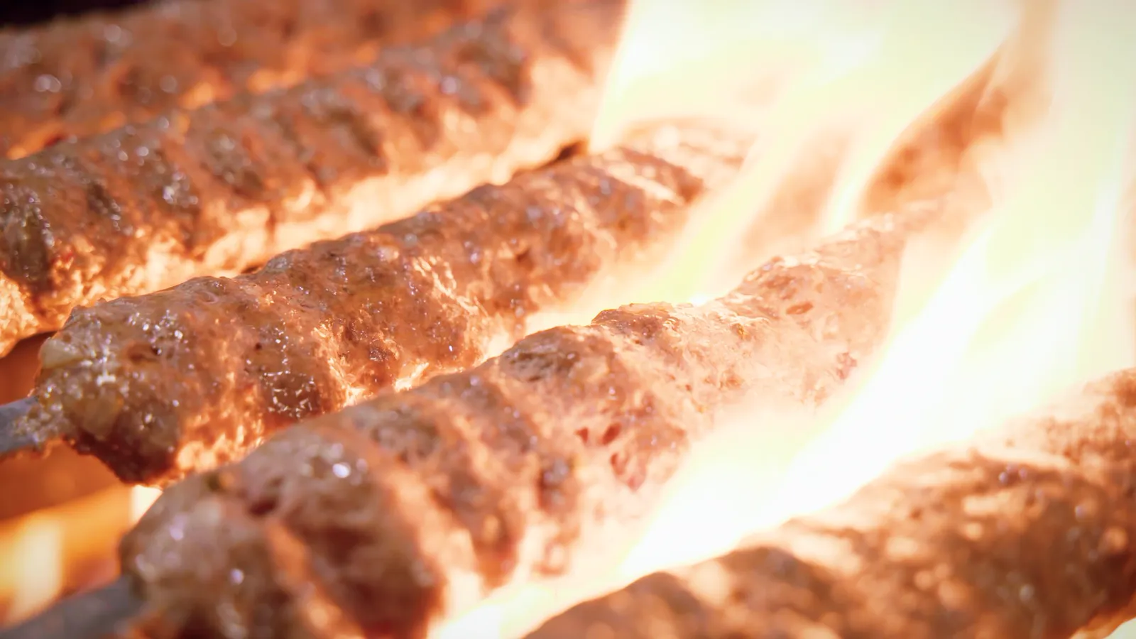 Adana kebab skewers cooking on the grill at Aladdin Grill
