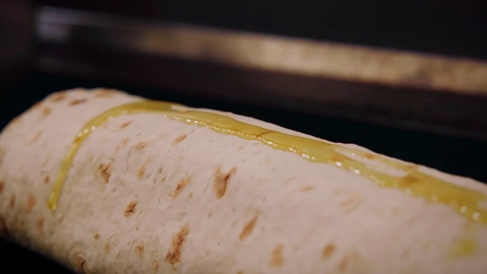Garlic butter being poured along a lavash roll