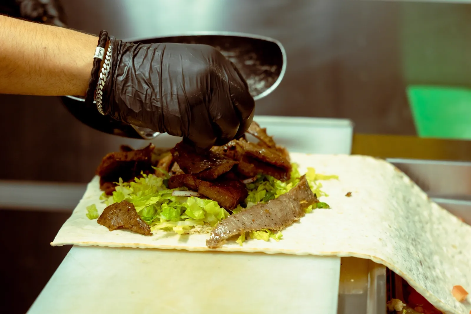 Shawarma being sliced onto a wrap at Aladdin Grill