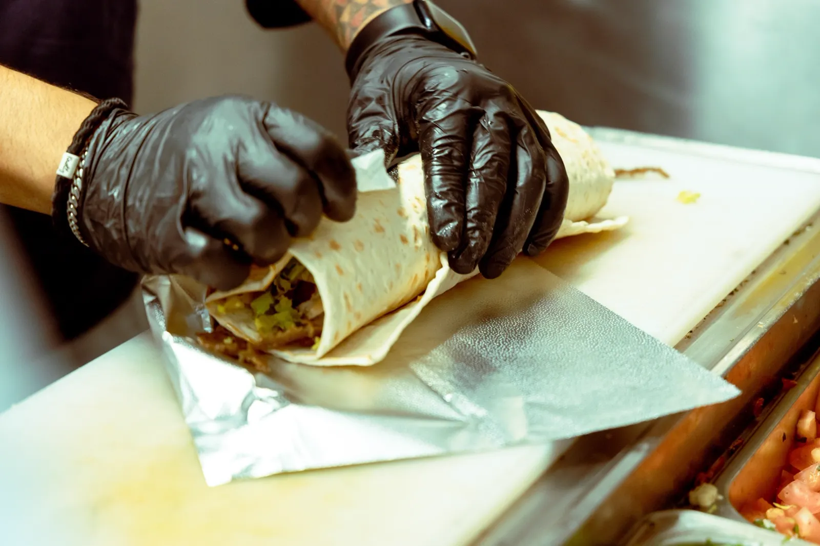 A shawarma wrap being rolled tightly in foil at Aladdin Grill