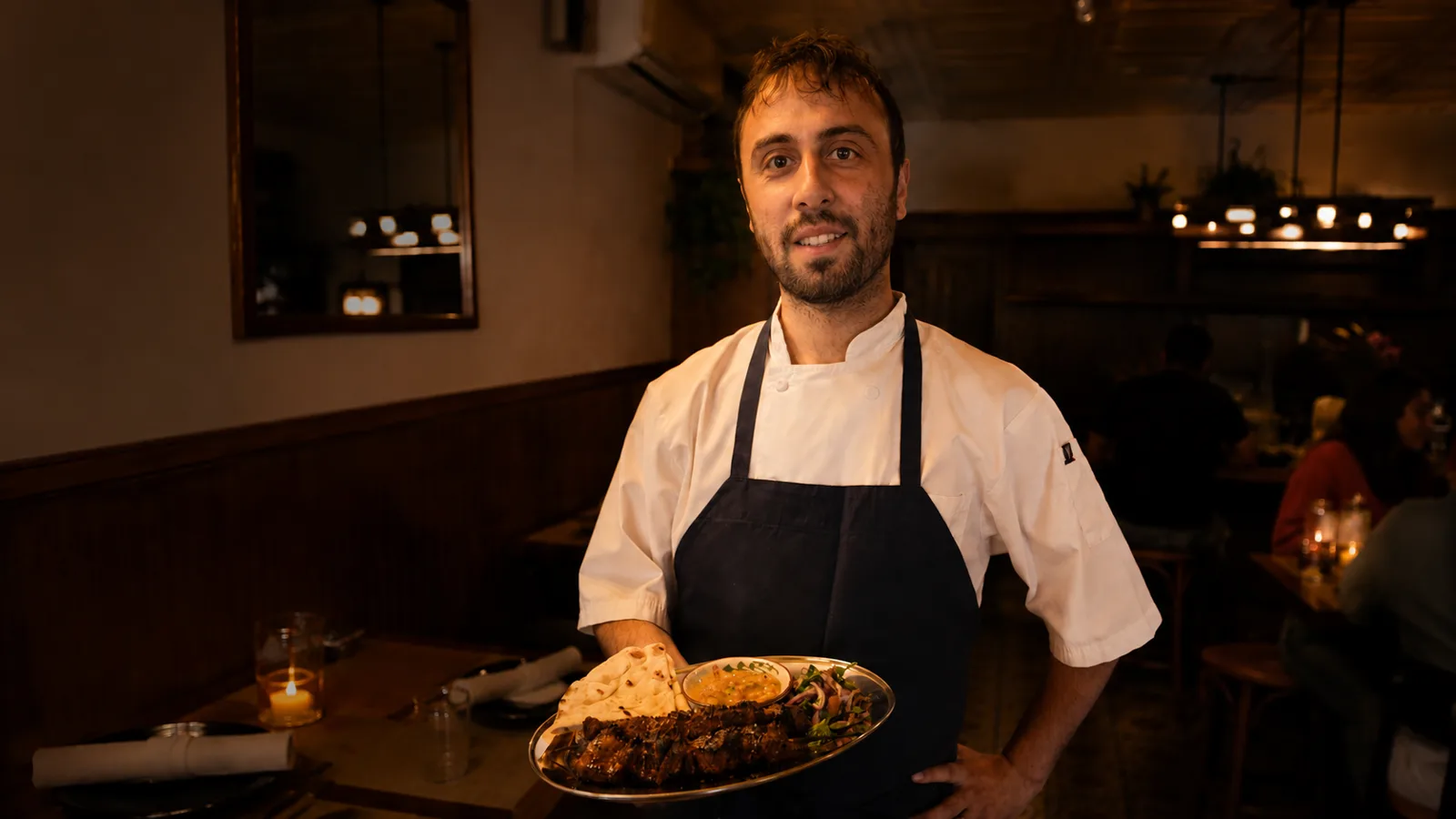 A chef at Alesta Modern Mediterranean holding a finished dish in the dining room