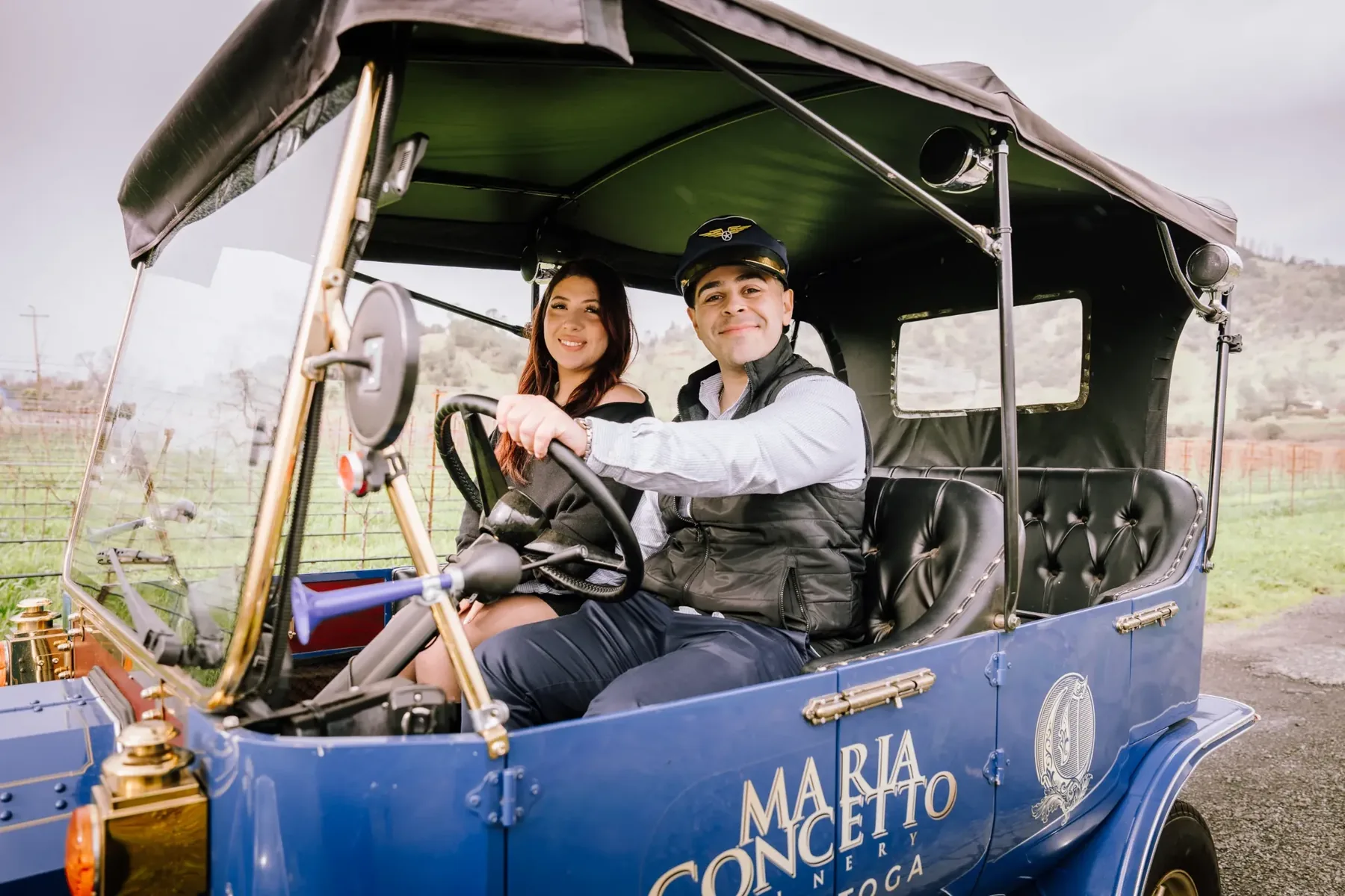 A couple riding through the vineyard in a vintage car at Maria Concetto Winery