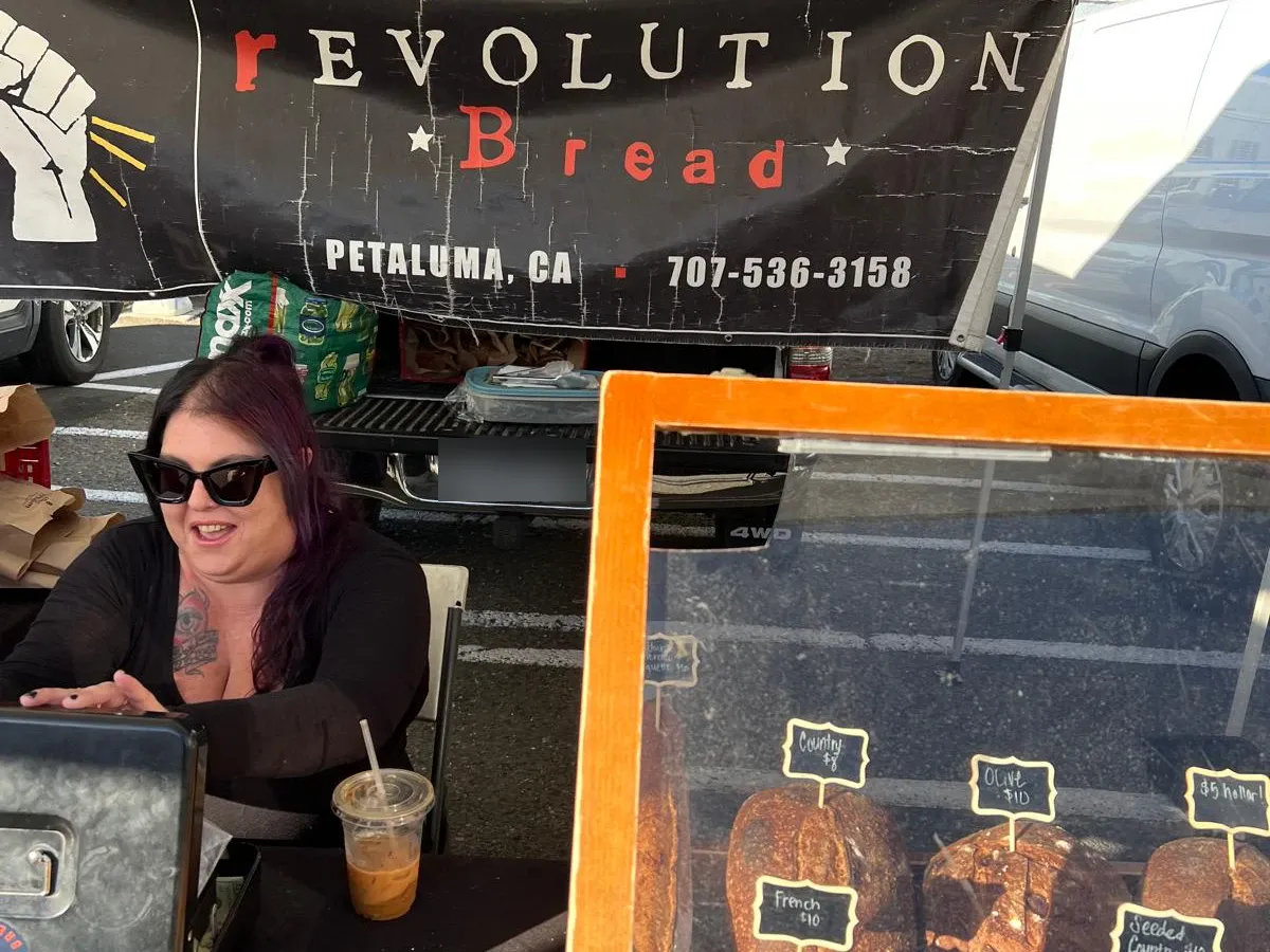 The Revolution Bread banner and a display case of loaves with chalkboard price tags
