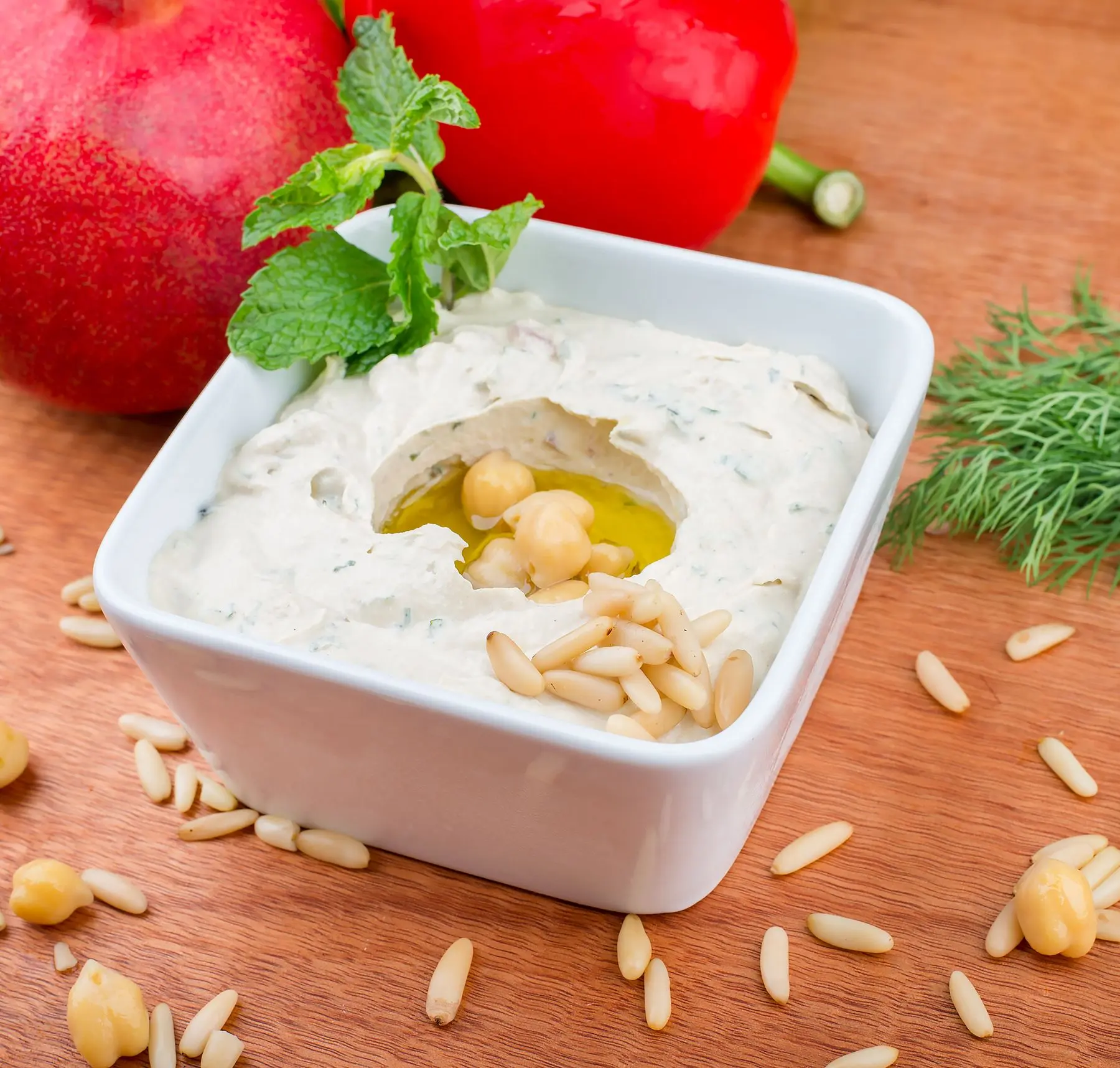 A bowl of creamy hummus finished with chickpeas, pine nuts and mint