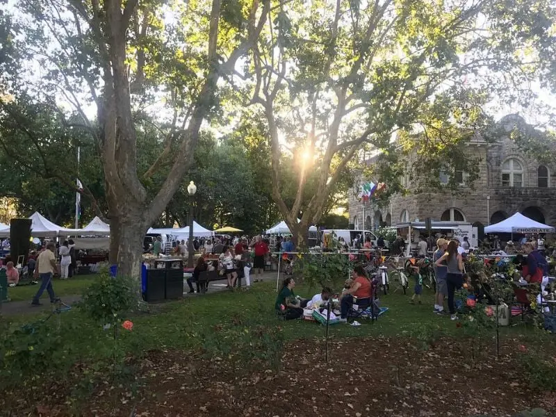 Evening market tents and visitors beneath the trees of Sonoma Plaza