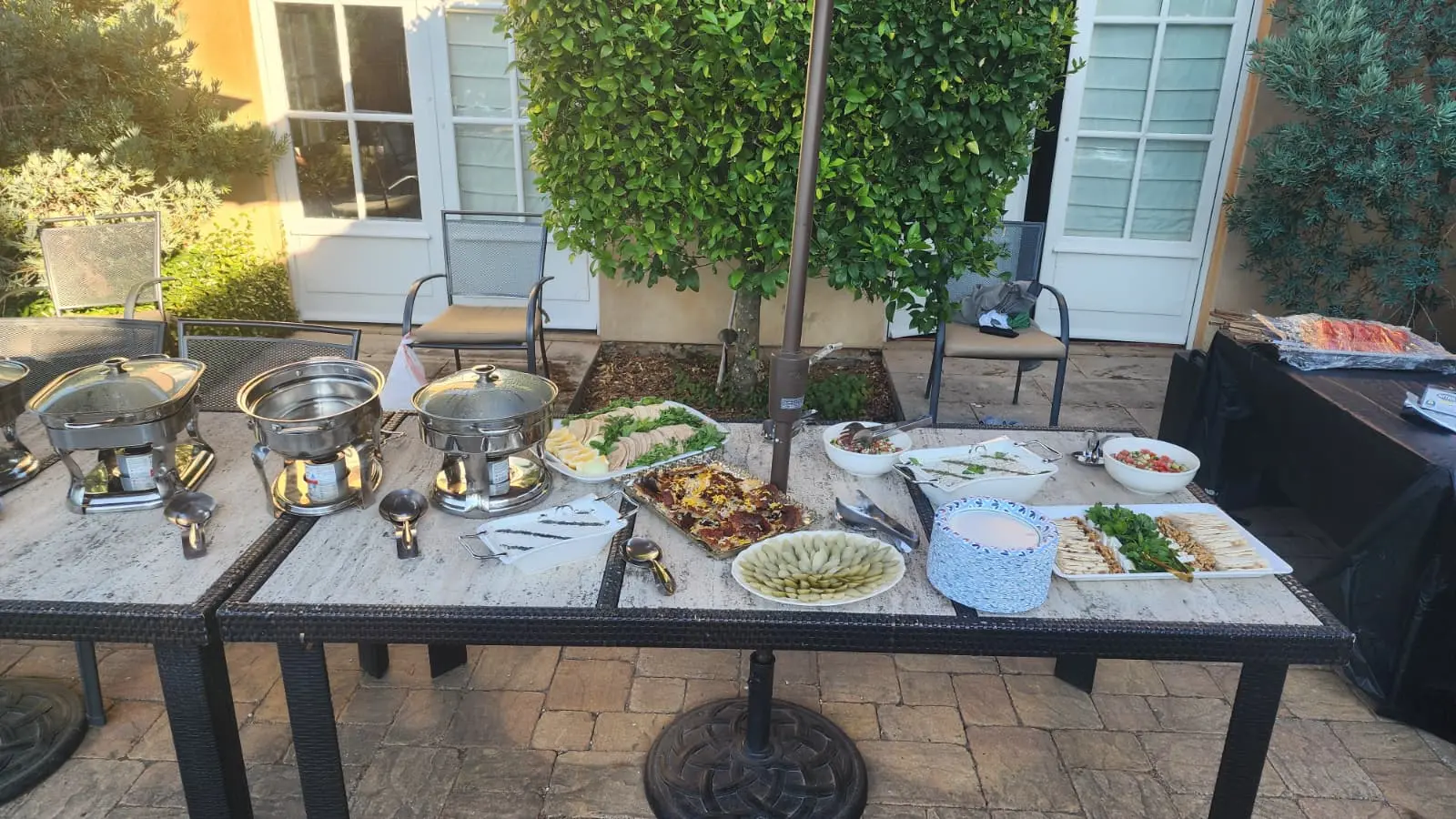 An outdoor Saffron catering setup with chafing dishes and a table of Persian food